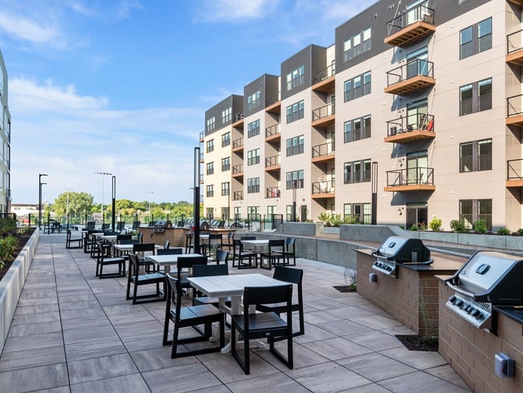 an outdoor patio with tables and chairs and an apartment building in the background